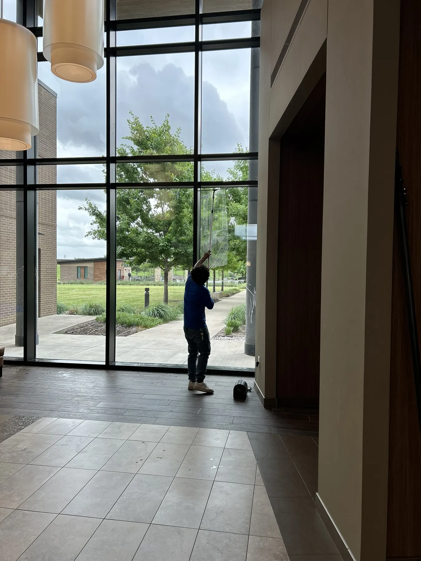 Technician cleaning tall interior commercial glass