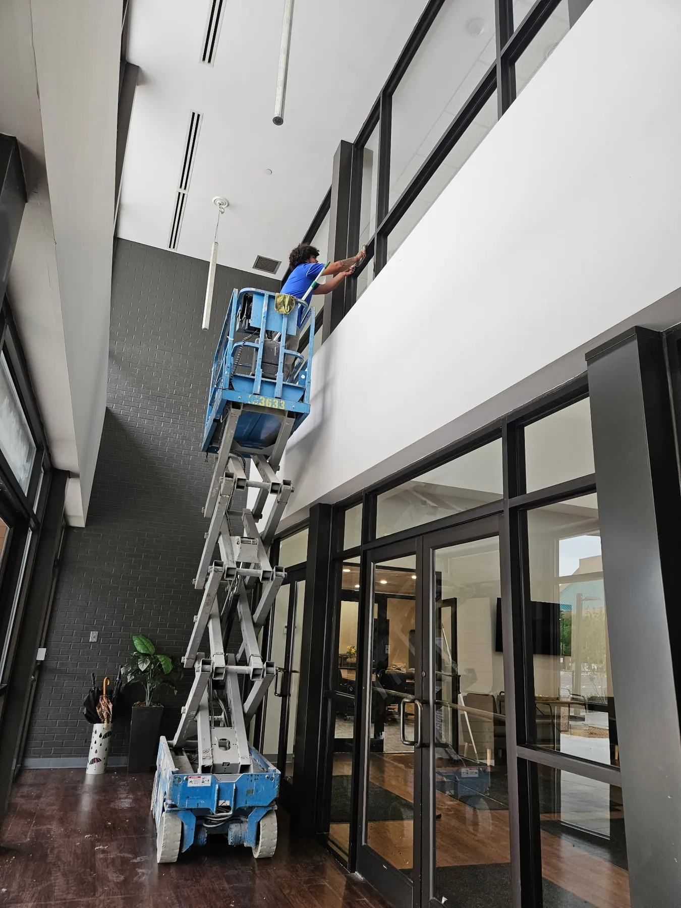 Technician in lift cleaning high interior windows